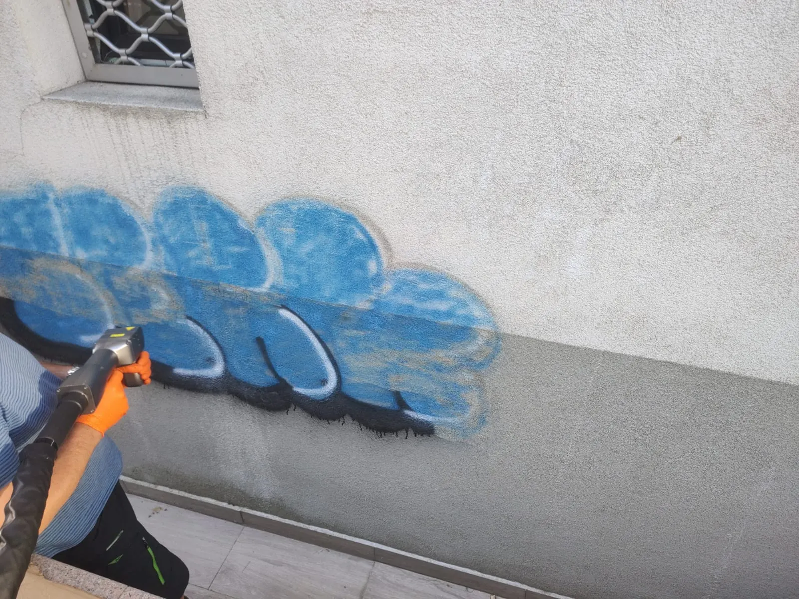 Laser în timpul curățării, cu jumătate din graffiti deja îndepărtată